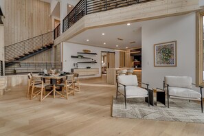 Ein geräumiger Wohnbereich mit hohen Decken, einer Treppe und einem Essbereich mit Holzsitzmöbeln.