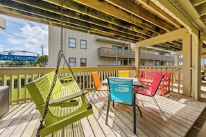 Une terrasse en bois avec une balançoire, des chaises et une table.