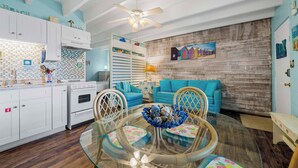 Una cocina con armarios blancos, una estufa y un comedor con mesa y sillas de vidrio.