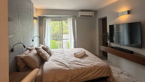A modern bedroom with a bed, a TV, and a window with curtains. - Stylish Loft Apartment Near Fishermans Village (Koh Samui)