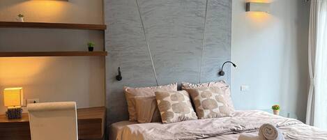 A modern bedroom with a bed, bedside tables, a desk, and a chair.