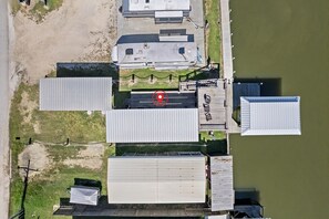 Luchtbeeld van een complex met meerdere gebouwen, een steiger en een omheind gebied.