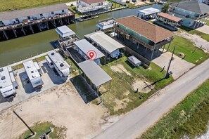 Luftaufnahme einer Marina mit vertäuten Booten, einem Gebäude mit rotem Dach und blauem Himmel.