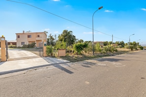 A residential street with houses, a sidewalk, and streetlights.