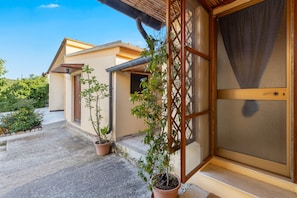 A building with a traditional design, a covered entrance, and potted plants.