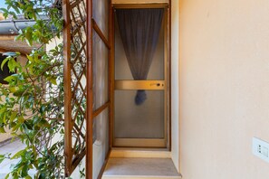 A door with a metal screen, a wooden lattice on the left, and a small step leading to the entrance. - Guest House 'Suite Simone' with Shared Garden and Air Conditioning (Pranixeddu)