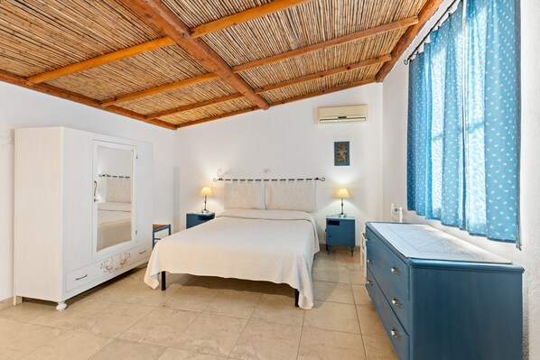 Une chambre à coucher comprenant un lit, une armoire, des tables de chevet et une fenêtre avec des rideaux.