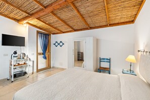 Une chambre à coucher comprenant un lit, un téléviseur, une armoire, une chaise, une lampe et une étagère avec divers objets.