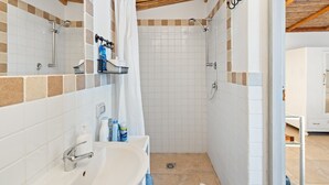 Un baño con ducha, lavamanos y espejo.