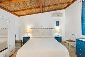 Une chambre à coucher comprenant un lit, deux tables de chevet, une armoire et un plafond avec des poutres en bois.