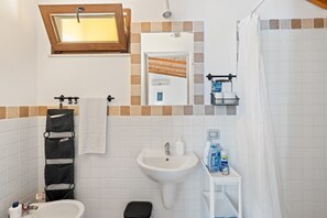 A bathroom with a sink, toilet, and shower curtain. - Guest House 'Suite Simone' with Shared Garden and Air Conditioning (Pranixeddu)