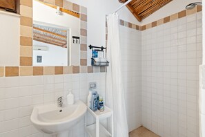A bathroom with a sink, mirror, shower, and tiled walls. - Guest House 'Suite Simone' with Shared Garden and Air Conditioning (Pranixeddu)