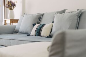 Ein Sofa mit vielen Kissen, eine Vase mit Blumen und ein Holztisch.