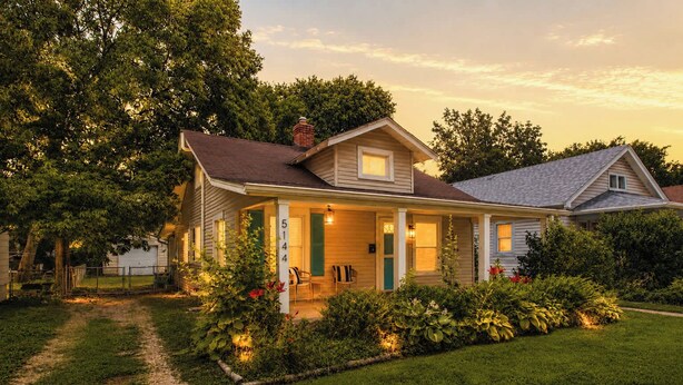 Ein zweistöckiges Haus mit Veranda, auf der Vorderseite ist die Hausnummer '5144' sichtbar, und ein gepflegter Garten.