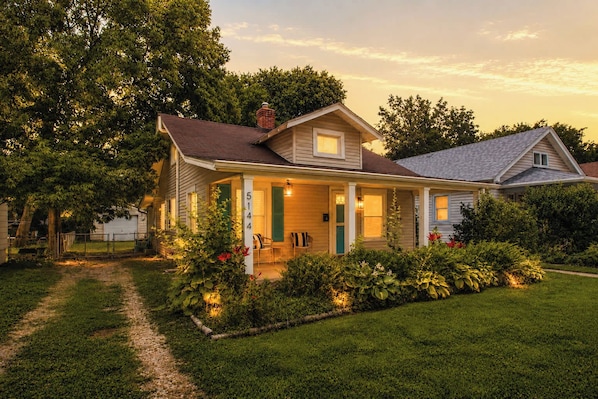 A two-story house with a porch, a visible number '5144' on the front, and a well-maintained garden.
