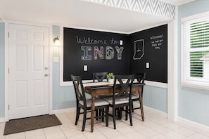 A dining area with a blackboard wall, a white door, and a window with blinds.