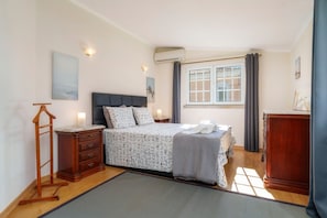 A bedroom with a bed, bedside tables, a wardrobe, a hanging rack, and a window with curtains. - Holiday Home 'Guatemala' with Private Pool, Wi-Fi and Air Conditioning (Quarteira)