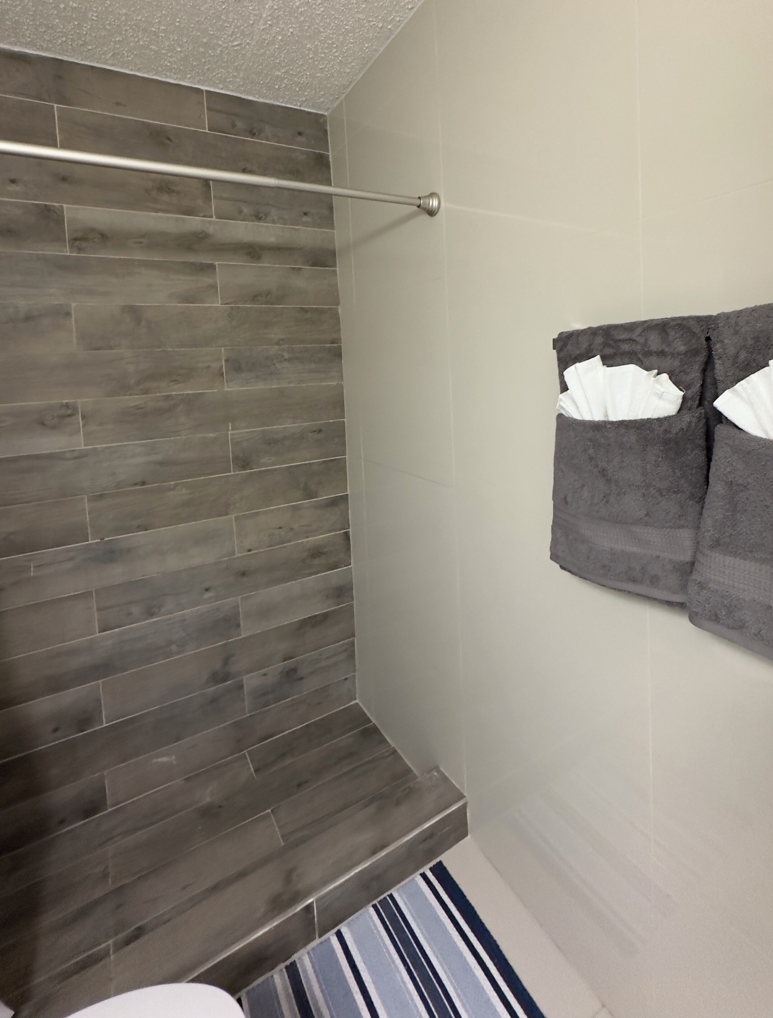 A bathroom with a wooden wall, a towel rack with towels, and a striped rug.