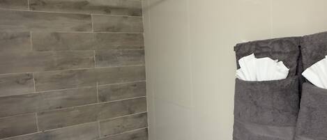 A bathroom with a wooden wall, a towel rack with towels, and a striped rug.