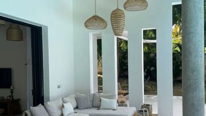 Ein modernes Wohnzimmer mit einem Ecksofa, einem Holztisch und gewebten Pendelleuchten.