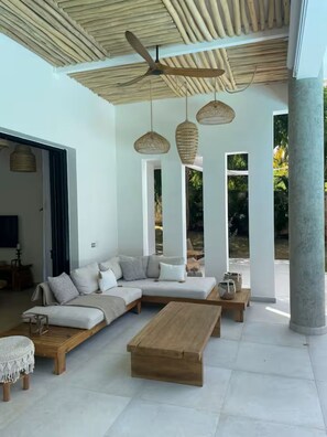 A modern living room with a sectional sofa, wooden coffee table, and woven pendant lights. - Villa Mana-5 Suites & Private Beach Access (El Portillo)