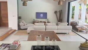 Ein modernes Wohnzimmer mit einer Sofagarnitur, einem Flachbildfernseher und einem Deckenventilator.
