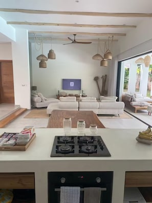 A modern living room with a sofa set, a flat-screen TV, and a ceiling fan. - Villa Mana-5 Suites & Private Beach Access (El Portillo)