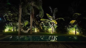 A nighttime view of a pool area with a hammock, palm trees, and a wooden deck. - Villa Mana-5 Suites & Private Beach Access (El Portillo)