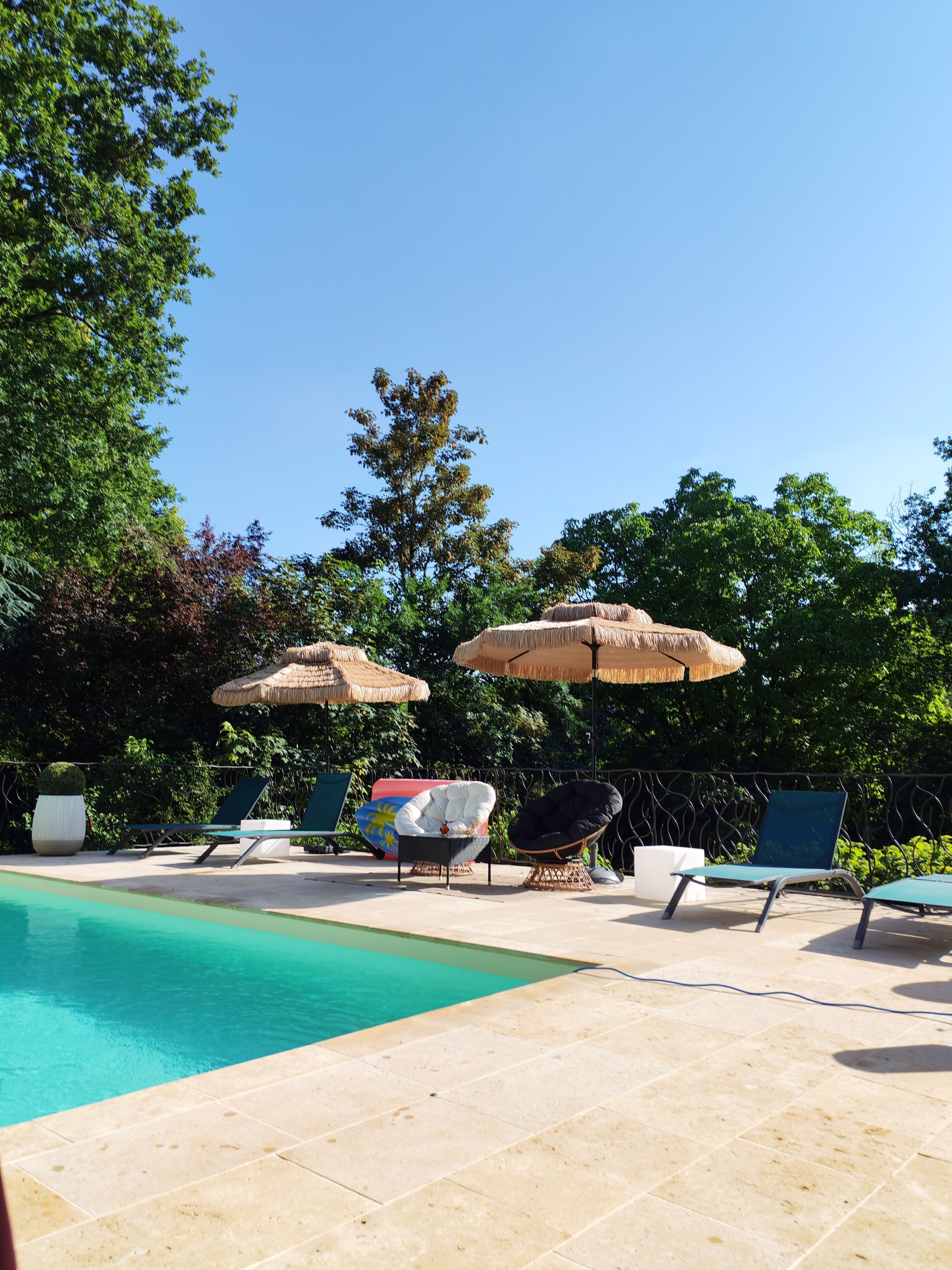 A pool area with lounge chairs and thatched umbrellas.