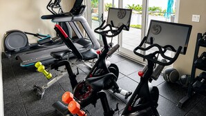 A home gym with exercise equipment, a treadmill, stationary bikes, and a rowing machine.