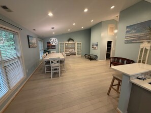 A spacious living area with a dining table, seating, and a view of the outdoors. - 3BR Beach Retreat – Short Walk to the Beach (Pine Knoll Shores)