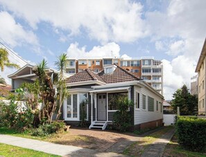 Une maison d’habitation avec un porche à l’avant, un petit jardin et une allée pavée.
