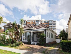 Ein Wohnhaus mit Veranda, kleinem Garten und blauem Himmel.