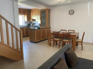Eine moderne Küche mit Holzausstattung, ein Essbereich mit Tisch und Stühlen sowie eine Treppe zu einer weiteren Ebene.