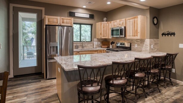 A kitchen with a central island, bar stools, stainless steel appliances, and wooden cabinets. - Modern Cabin in Beautiful Pinetop (Pinetop-Lakeside)
