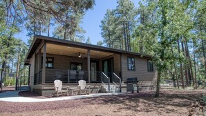 A cabin with a covered porch, outdoor seating, and a grill. - Modern Cabin in Beautiful Pinetop (Pinetop-Lakeside)