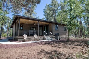 A cabin with a covered porch, outdoor seating, and a grill. - Modern Cabin in Beautiful Pinetop (Pinetop-Lakeside)
