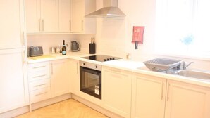 A kitchen with white cabinets, a stove, oven, and a window with a view. - Seaview Terrace - 5 Bedroom seaview home (Tyne and Wear)