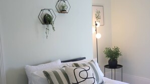 A neatly made bed with striped pillows, a small potted plant on a side table, and two hexagonal wall decorations. - Seaview Terrace - 5 Bedroom seaview home (Tyne and Wear)
