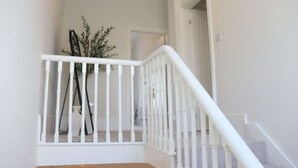 A white staircase with a railing, a plant in a black pot, and a door at the top. - Seaview Terrace - 5 Bedroom seaview home (Tyne and Wear)