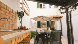 Eine Terrasse mit einer Ziegel-Theke, einem Tisch, Stühlen und einem Sonnenschirm.