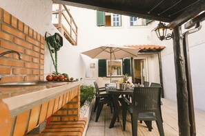 Eine Terrasse mit einer Ziegel-Theke, einem Tisch, Stühlen und einem Sonnenschirm.