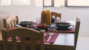 Ruokapöytä on katettu lautasilla, laseilla, punaisella aluslautasella ja kahdella juomapullolla.