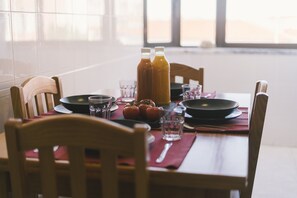 A dining table set with plates, glasses, a red placemat, and two bottles of a beverage. - Best Houses 62 - Praia da Baia Apartment (Peniche)
