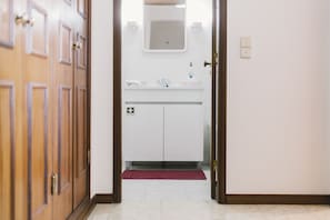 A hallway leading to a bathroom with a white sink, a mirror, and a red rug. - Best Houses 62 - Praia da Baia Apartment (Peniche)