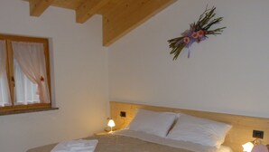 Un dormitorio con una cama de madera, dos mesitas de noche, una ventana con cortinas y un adorno en la pared.