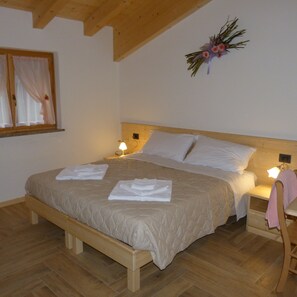 Ein Schlafzimmer mit einem hölzernen Bett, zwei Nachttischen, einem Fenster mit Vorhängen und einer Wanddekoration.