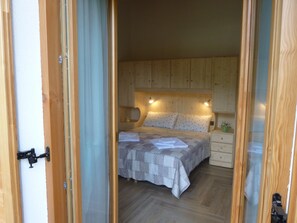Ein Schlafzimmer mit hölzernem Kopfteil, einem Bett mit Steppdecke, einem Nachttisch und einer kleinen Pflanze.