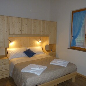 Un dormitorio con cama de madera, mesitas de noche y una ventana con cortinas.