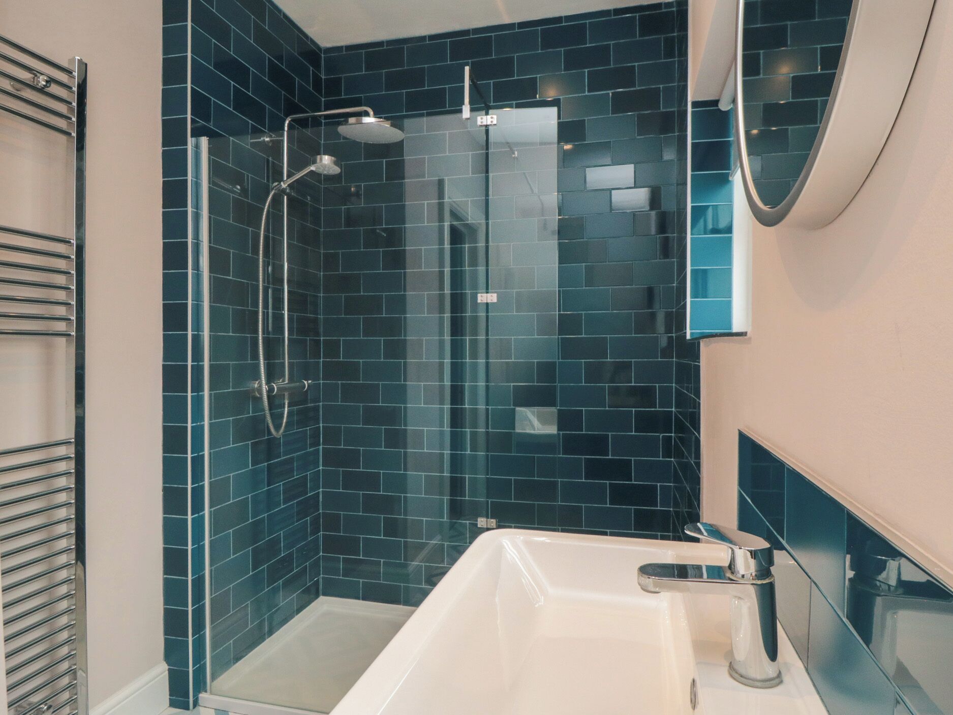 A modern bathroom with a glass-enclosed shower, a white bathtub, and a mirror above the sink.